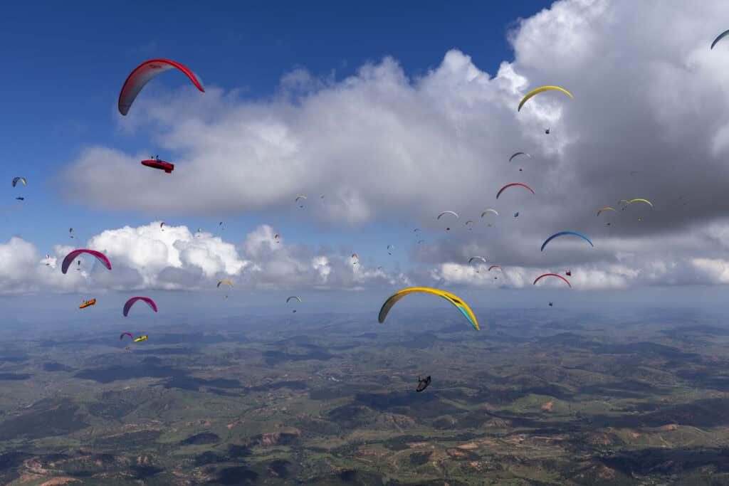 Competition pilot gliding between thermals during a Paragliding World Cup task